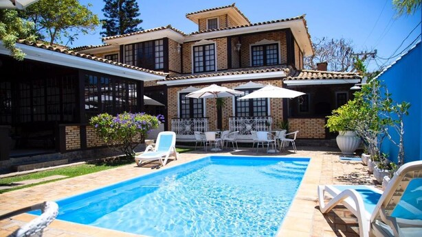 A two-story house with a swimming pool, outdoor furniture, and a patio area. - Pousada Casa da Praia (Búzios)
