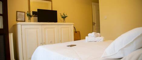 Una habitación de hotel con una cama, un televisor sobre un mueble y un espejo en la pared.