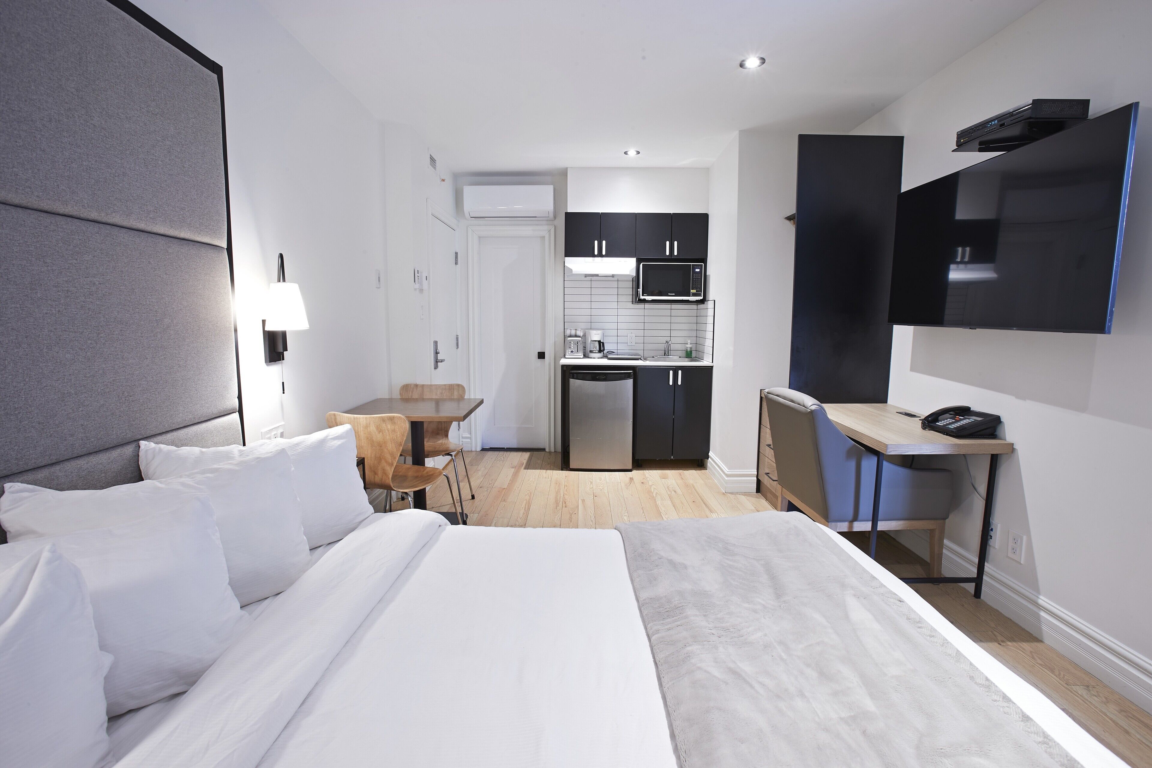 Une chambre d’hôtel moderne équipée d’un grand lit, d’un bureau, d’une kitchenette et d’un téléviseur à écran plat.