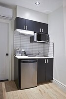 Une cuisine de taille réduite avec des meubles noirs, un four à micro-ondes, un grille-pain et un lave-vaisselle.