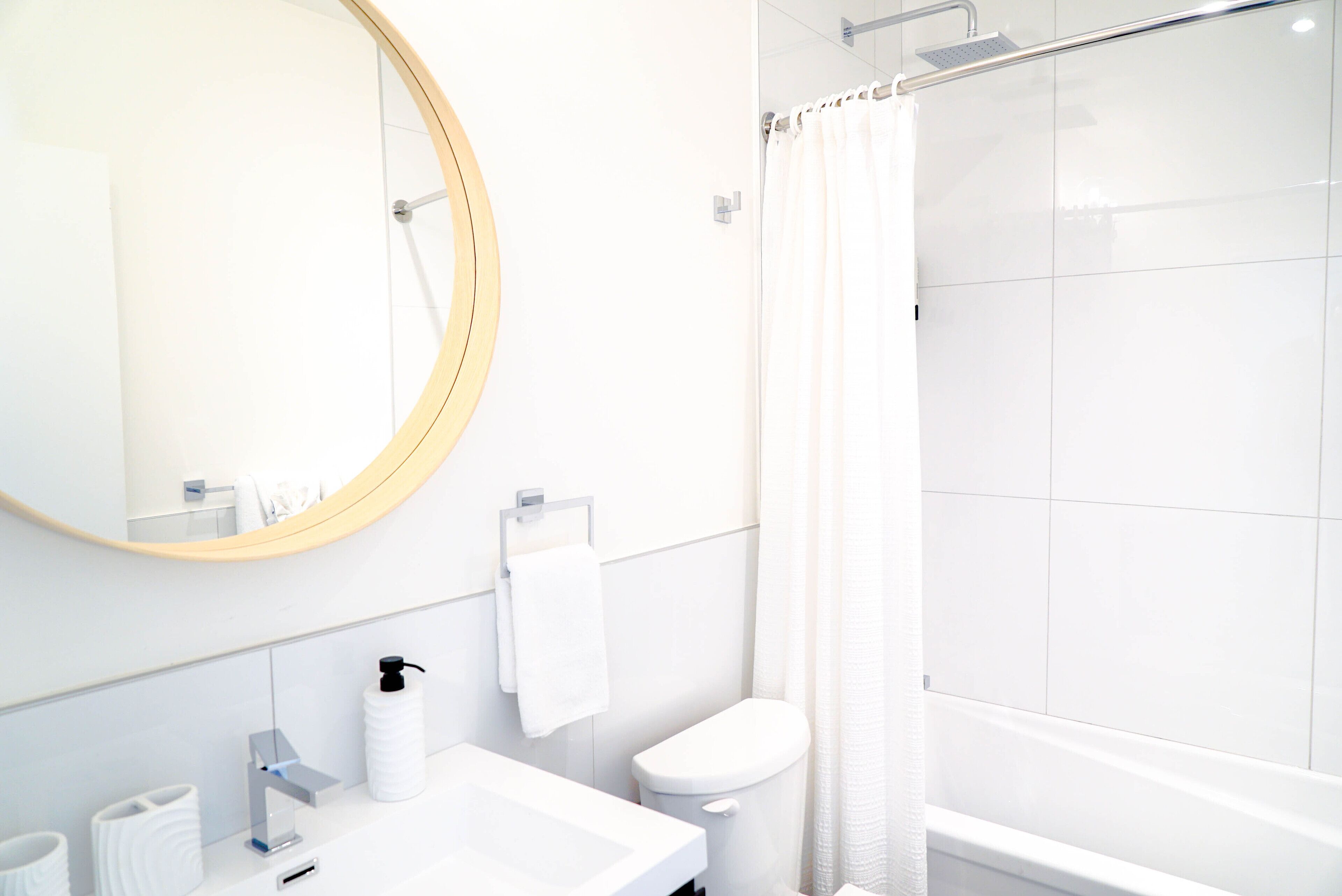 Een moderne badkamer met een ronde spiegel, een wit wastafelmeubel en een douche.