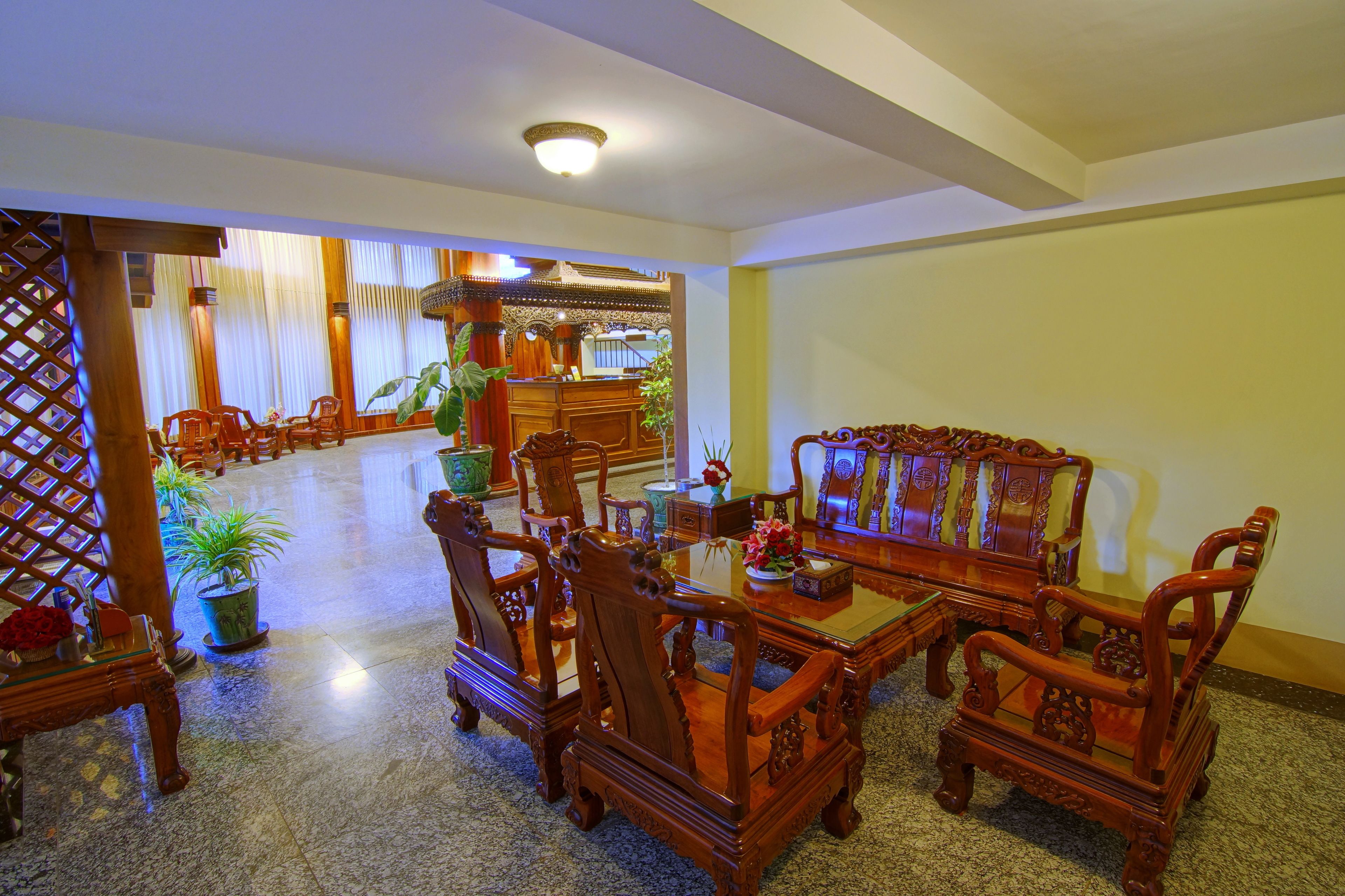 Un comedor tradicional de madera con una mesa, sillas, plantas en macetas y un aparador decorativo.