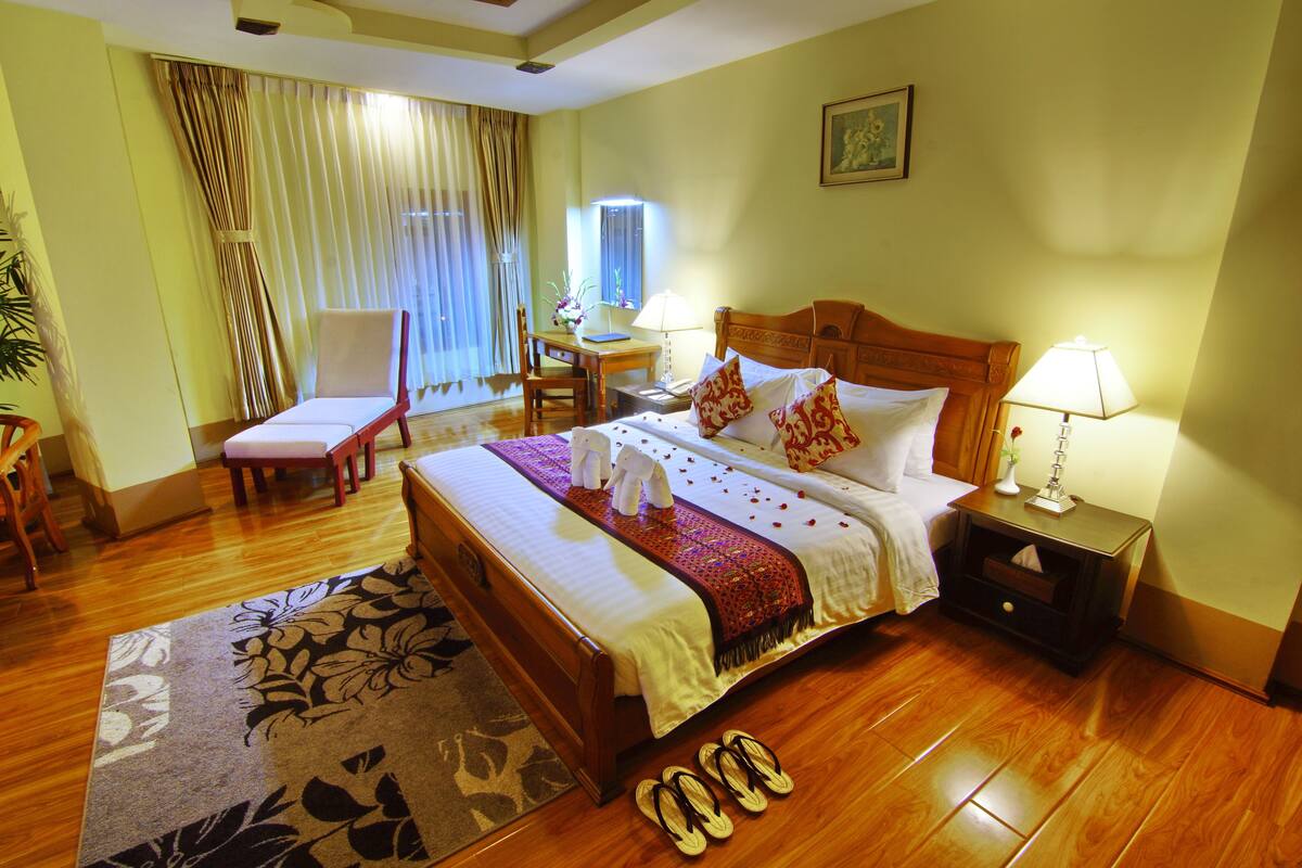 A hotel room with a large bed, a desk, a chair, and a nightstand.