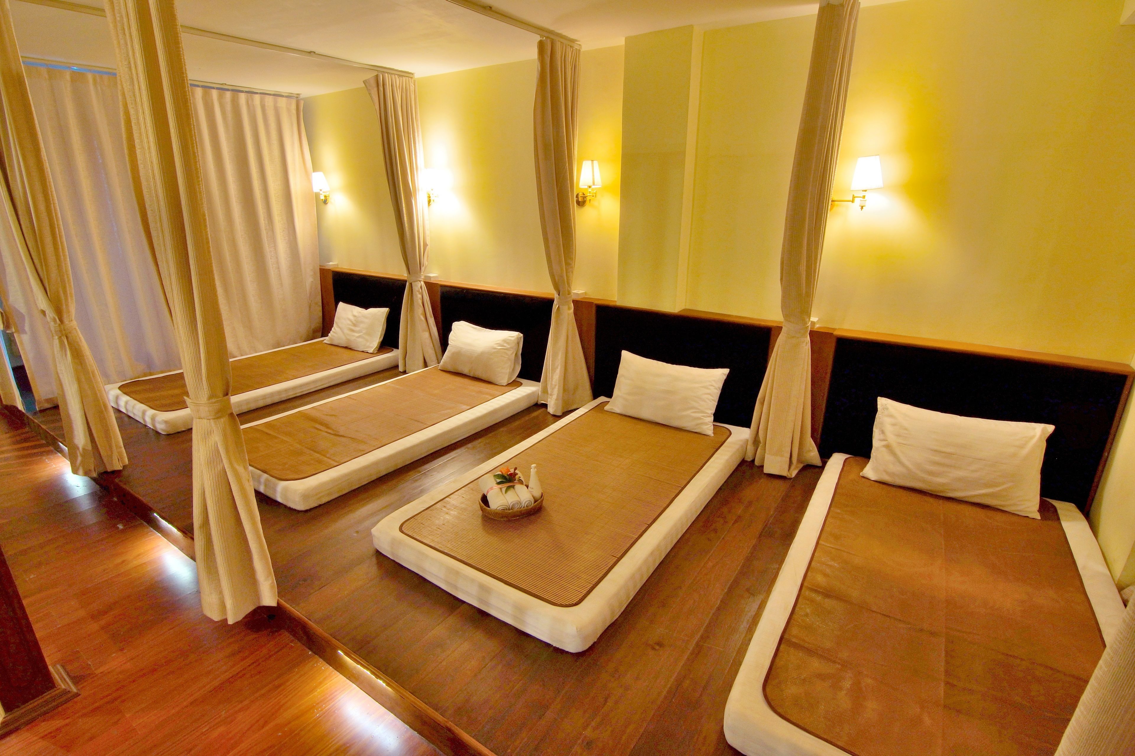 A room with four beds arranged in a row, each with a canopy.