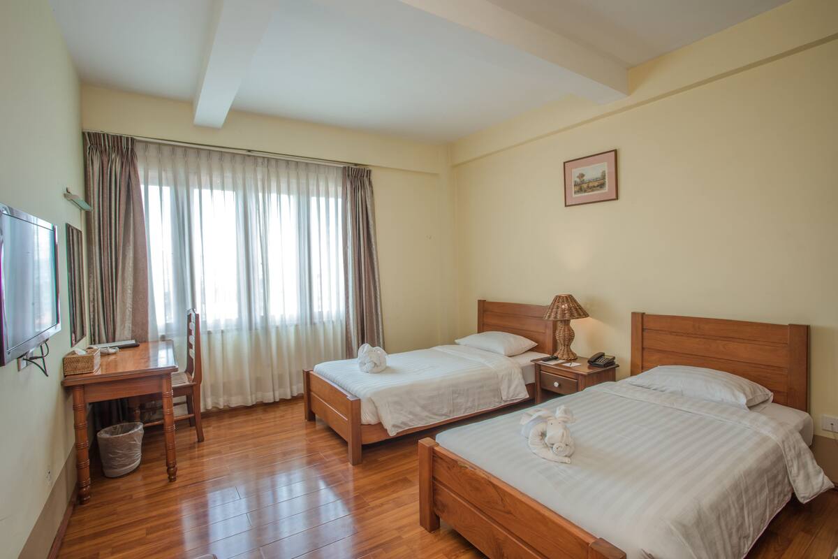 A hotel room with two beds, a desk, and a chair.