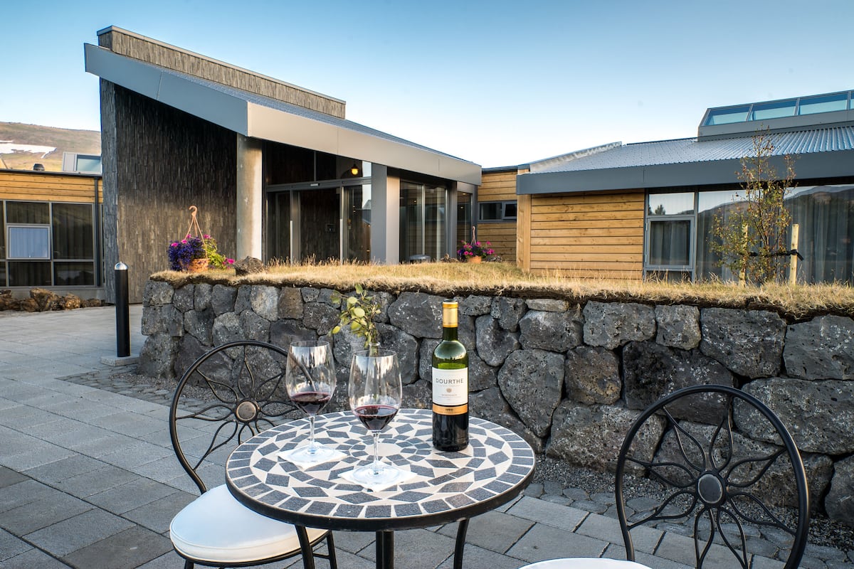 A modern outdoor seating area with a table, chairs, and a bottle of wine.