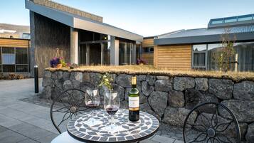 Un espace extérieur moderne aménagé avec une table, des chaises et une bouteille de vin.
