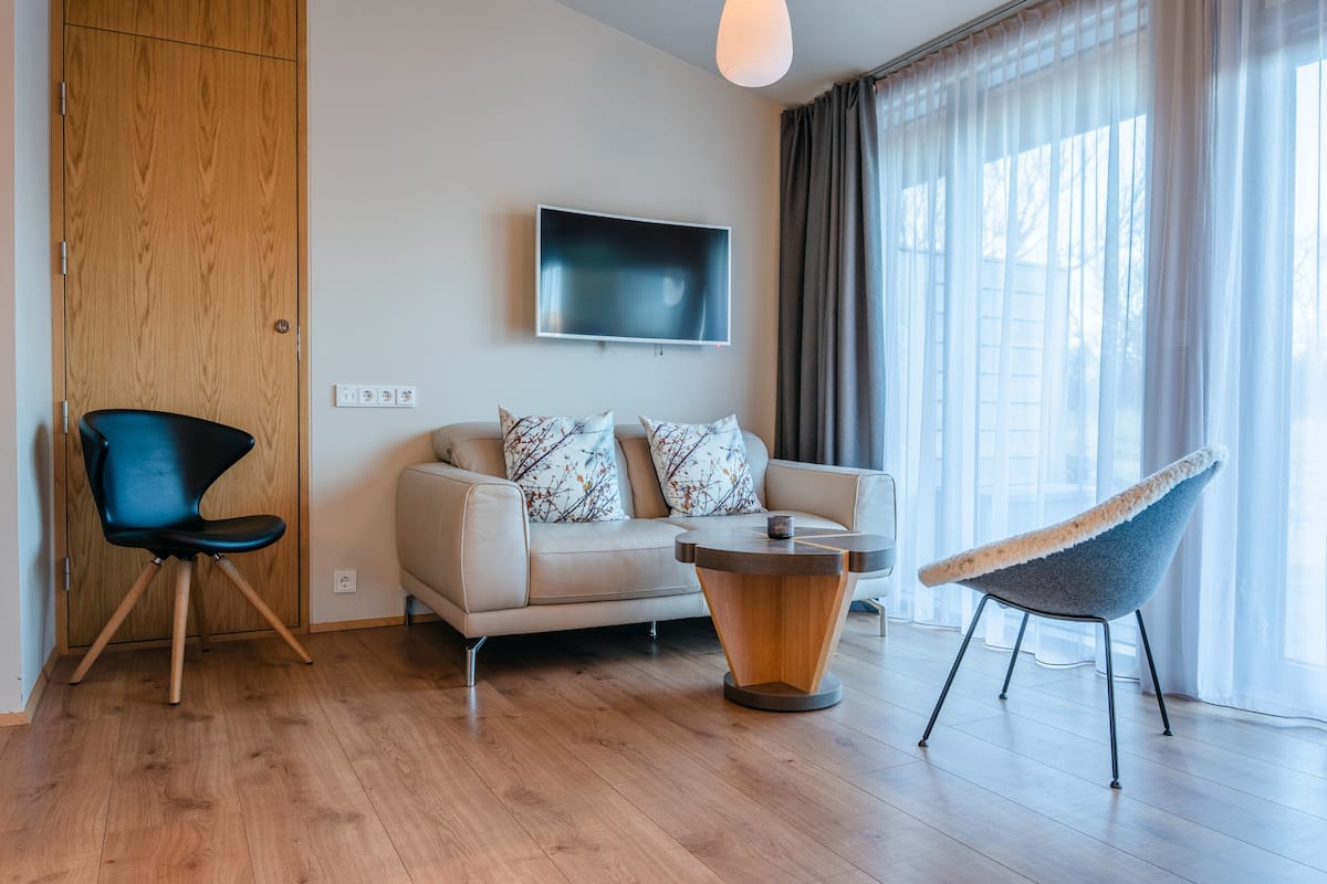 A modern living room with a sofa, two chairs, a coffee table, and a TV mounted on the wall.