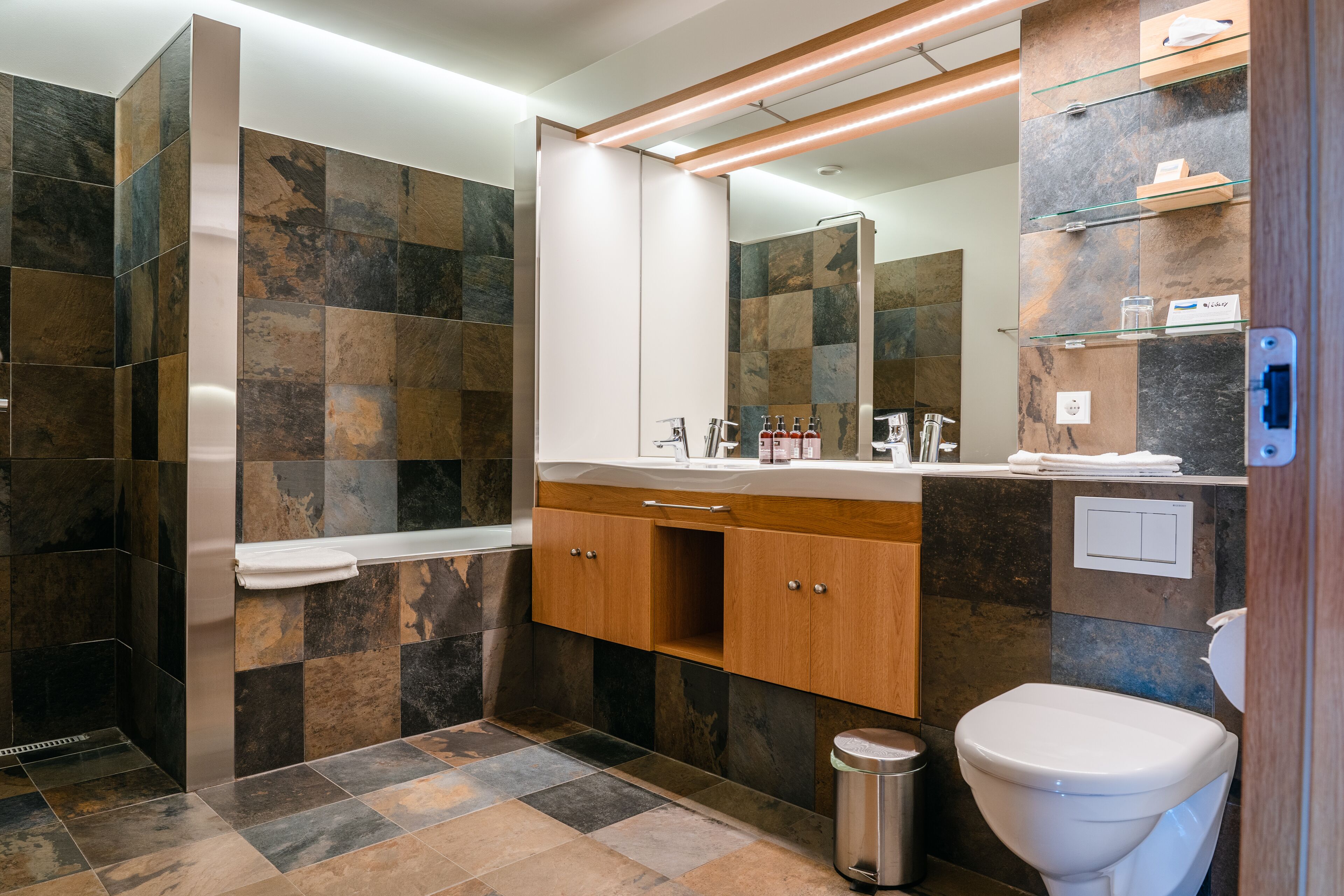 A modern bathroom with a checkered tile floor, a wooden vanity with a mirror, and a white toilet.