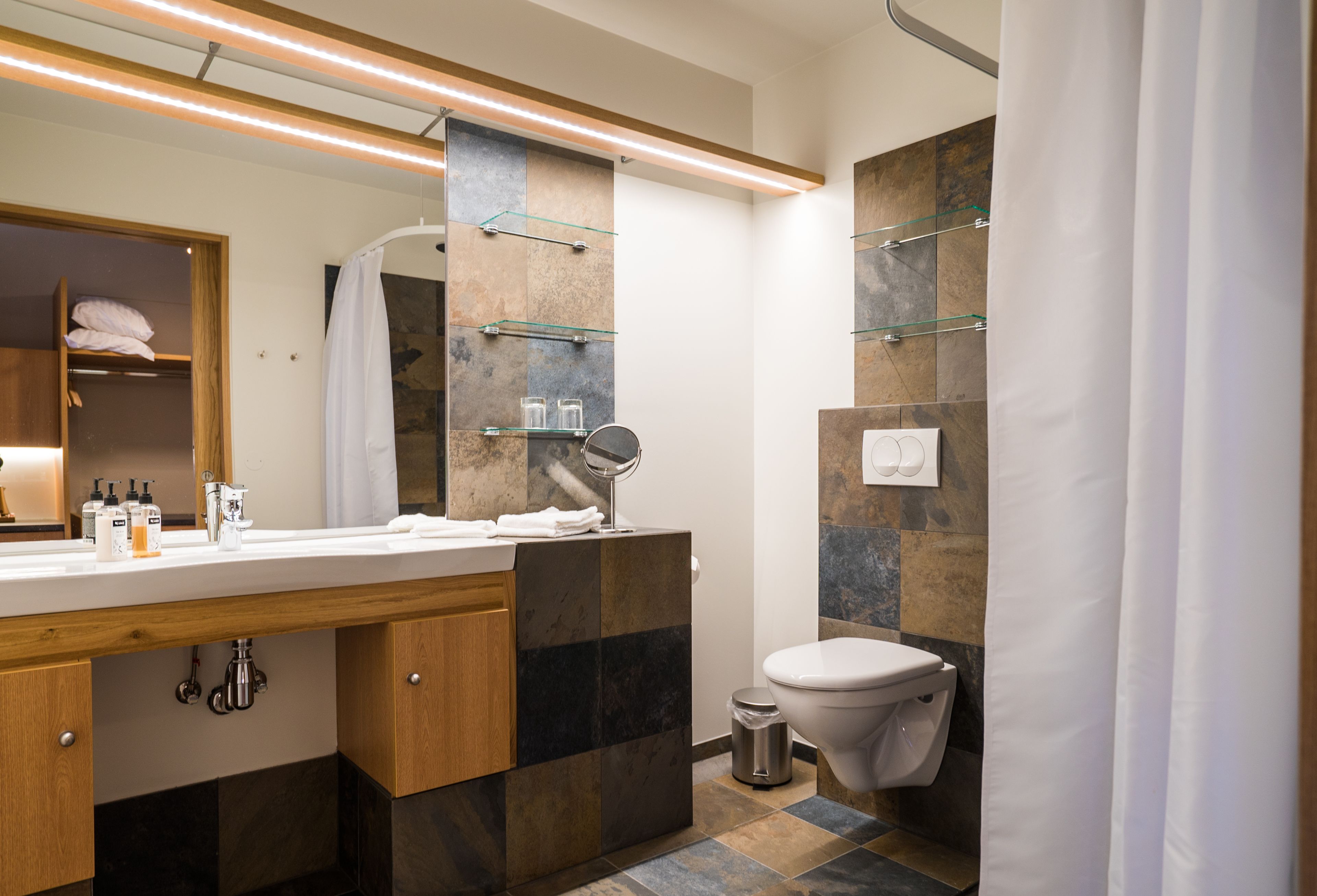 Un baño moderno con tocador de madera, un espejo grande y un inodoro.