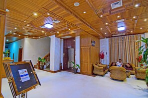 A lobby with wooden ceiling, wicker furniture, and potted plants. - Hotel 76 (Mandalay)