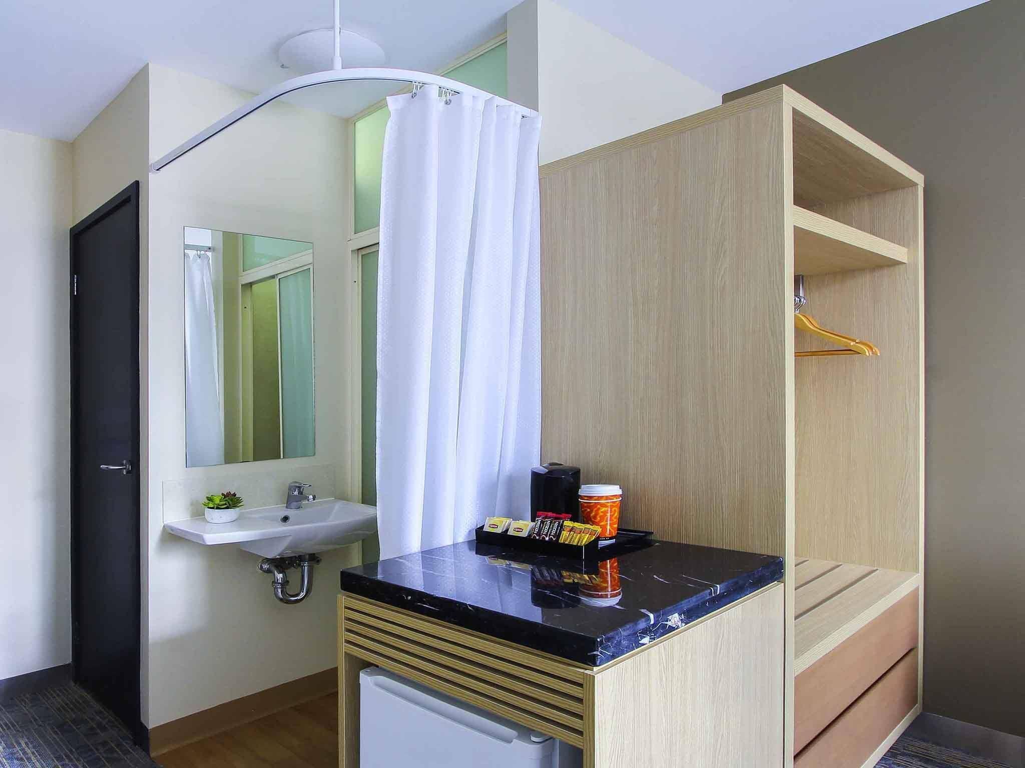 A compact bathroom with a sink, mirror, and shower curtain.
