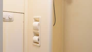 Un baño con inodoro, ducha y dispensador de papel higiénico.