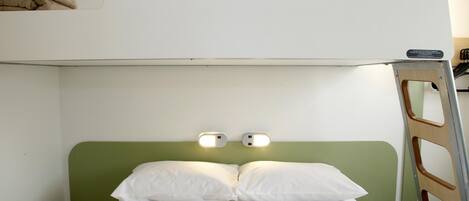 Una cama litera con cabecera verde, dos lámparas de noche y una escalera.