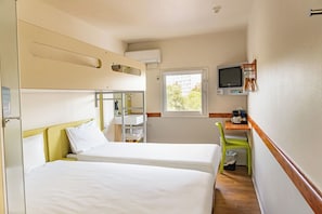 A compact hotel room with two beds, a small desk with a chair, a television, and a window providing natural light. - ibis budget Melbourne Airport (Melbourne Airport)