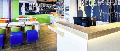 Un restaurant moderne avec des tabourets colorés, un comptoir et un mur où sont exposés divers objets.