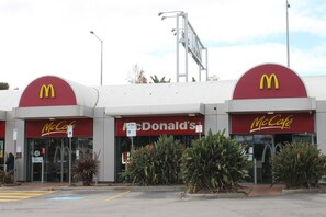Een McDonald's restaurant met een rood en geel logo, een drive-thru en een parkeerplaats.