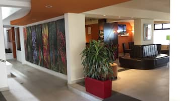 A modern lobby with a curved ceiling, a reception desk, a seating area, and a large wall with floral artwork.