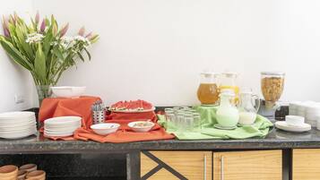 A kitchen counter with various items including plates, bowls, a pitcher, and a vase with flowers.