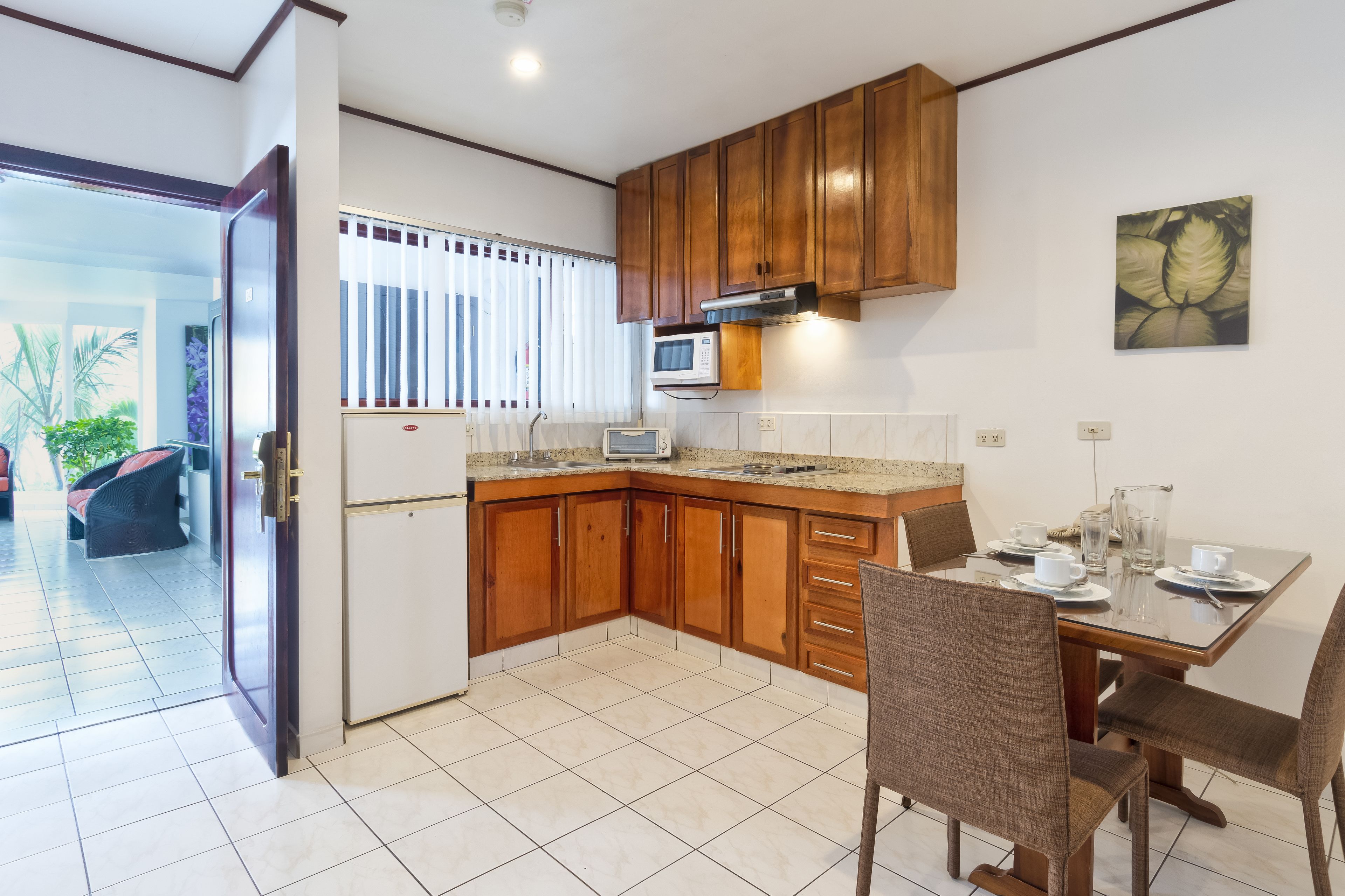 A kitchen with wooden cabinets, a microwave, and a dining table set for four.
