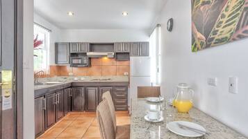 A modern kitchen with dark cabinets, a granite countertop, and a dining area with a table set for two.