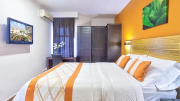 A hotel room with a bed, a desk, a chair, a wardrobe, and a picture on the wall.