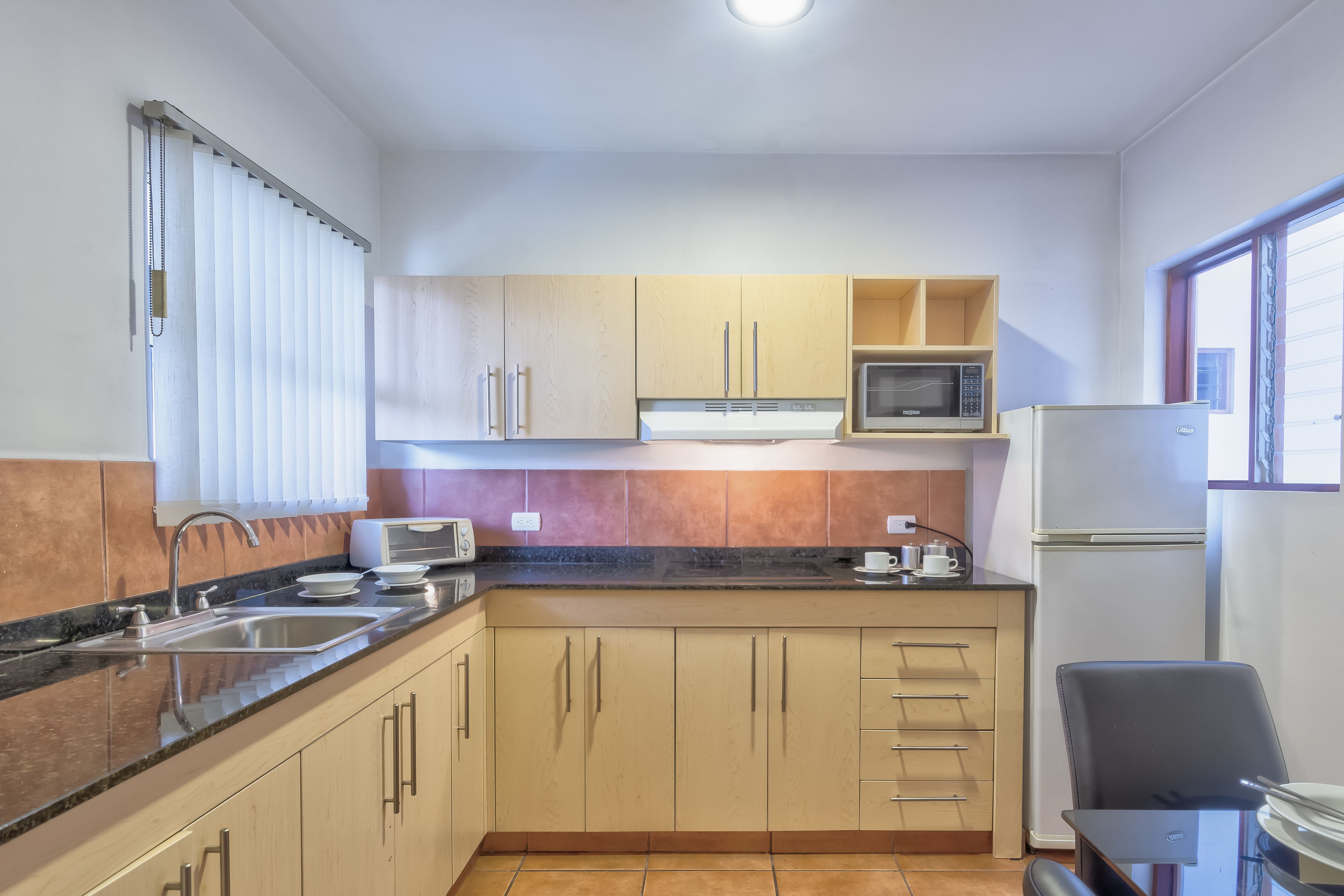 A compact kitchen with a sink, microwave, and refrigerator.