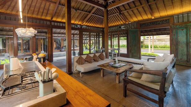 A spacious indoor area with a high ceiling, wooden beams, and a seating area with sofas and a table. - Puri Tupai (Ubud)