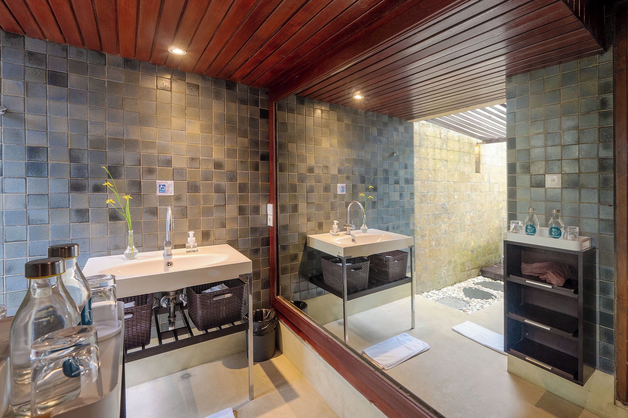 Un baño con dos lavamanos, un espejo y una pared con azulejos.