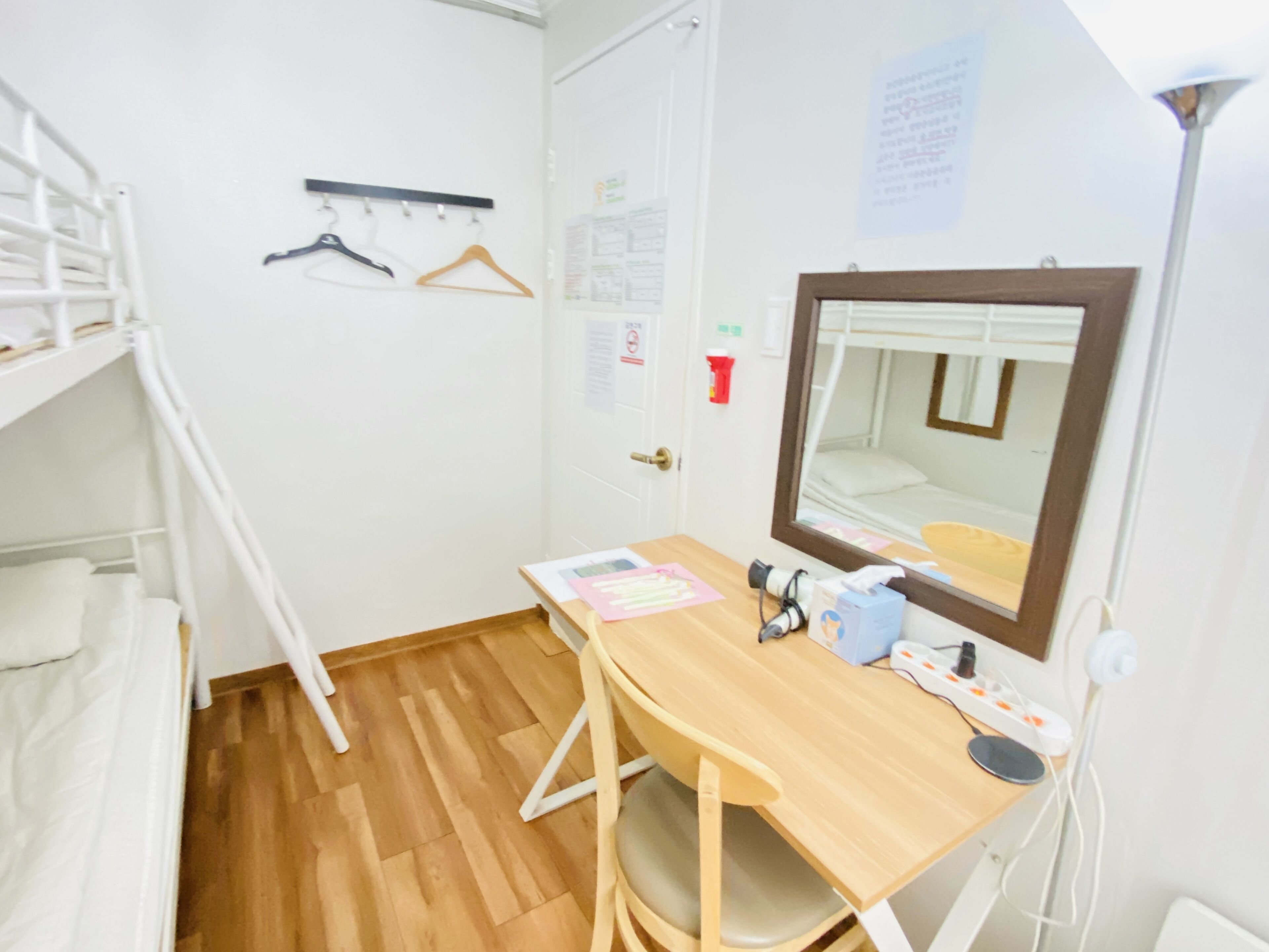 Un dormitorio con literas, un escritorio, un espejo y un tablón de anuncios.