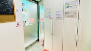 A hotel corridor with a glass door, a passcode board, and a wardrobe with a sign. - Aroha Guest House (Seoul)