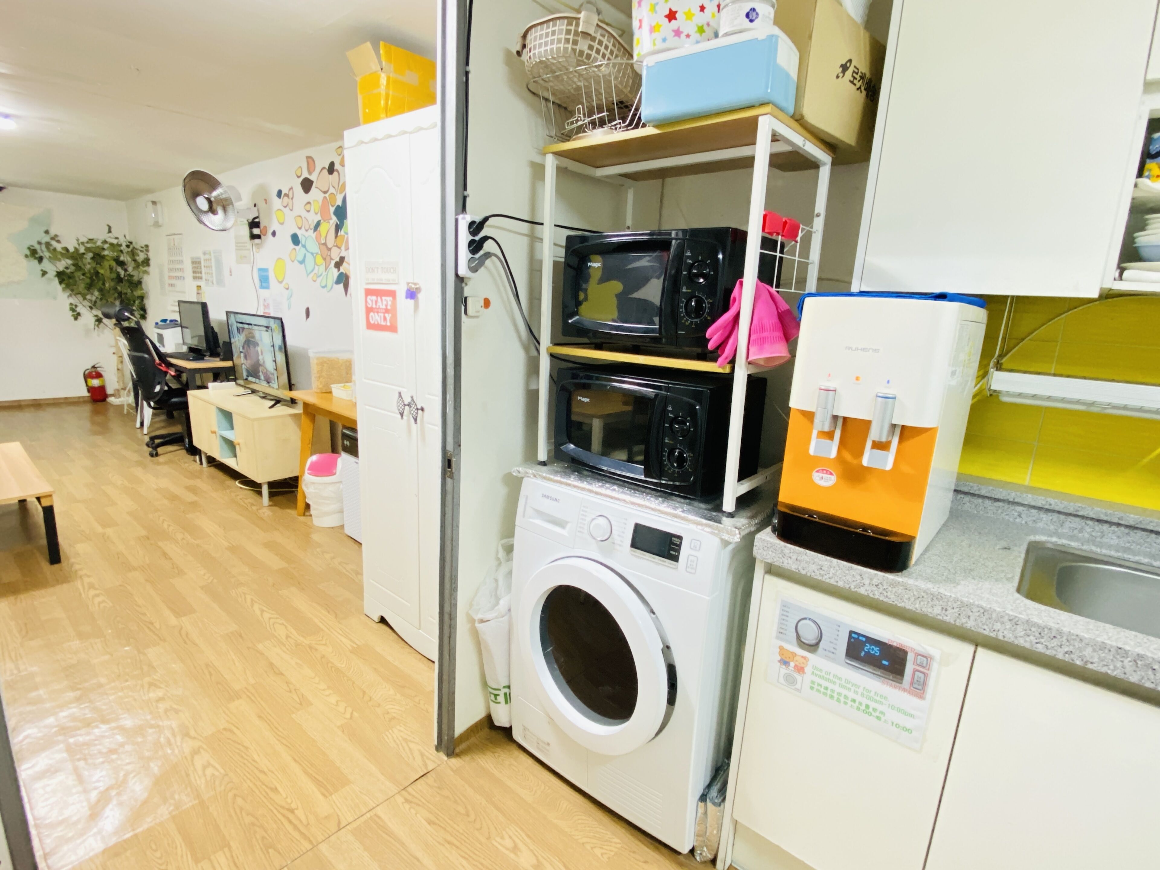 A laundry room with a washing machine, dryer, microwave, and a shelf with various items.