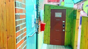 A narrow corridor with a wooden door labeled "Luggage Storage" and a sign for "Aroha Guest House". - Aroha Guest House (Seoul)
