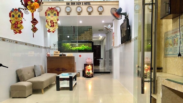 A hotel lobby with a sofa, a small table, a reception desk, and a decorative altar. - Saigon Cozy2 Hotel (Ho Chi Minh City)