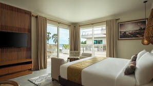 A hotel room with a large bed, a flat-screen TV, a balcony with a view of the ocean, and a dining area with a table and chairs. - Anantara Vacation Club Legian (Legian)