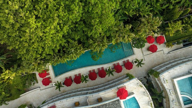 An aerial view of a resort with a swimming pool, red umbrellas, and palm trees. - Anantara Vacation Club Legian (Legian)
