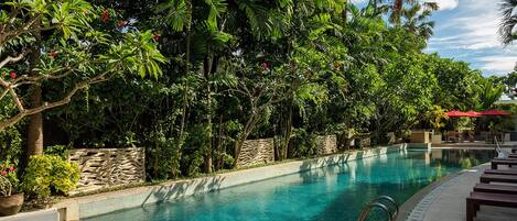 A pool surrounded by lush greenery and stone walls.