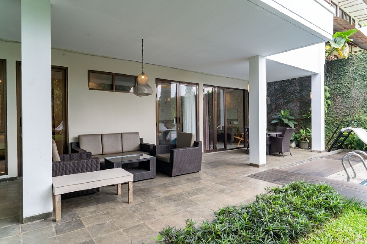 A covered outdoor seating area with a sofa, chairs, and a table.