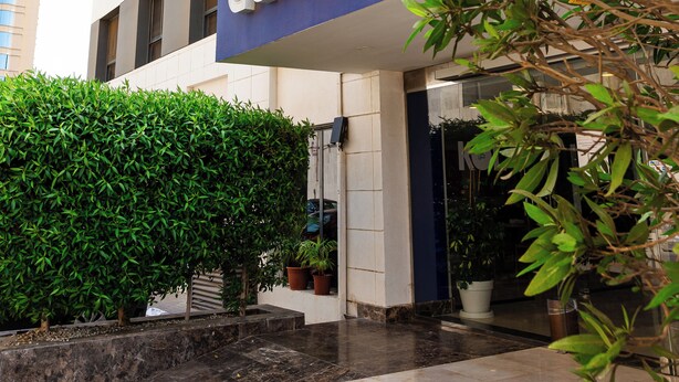 L’entrée d’un hôtel, avec une enseigne indiquant « data b b b » et un beau parterre bien entretenu devant.