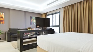 Une chambre d’hôtel moderne dotée d’un grand lit, d’un téléviseur à écran plat, d’un canapé et d’une table à manger.