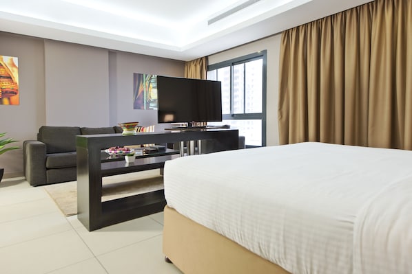 Une chambre d’hôtel moderne dotée d’un grand lit, d’un téléviseur à écran plat, d’un canapé et d’une table à manger.