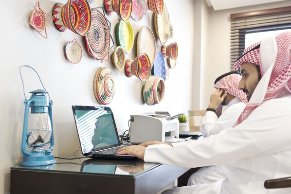 A person working on a laptop in a room with a wall decorated with woven baskets. - Dara Salam (Jeddah)