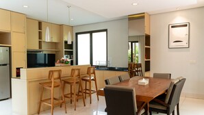 A modern kitchen with a central island, wooden chairs, and a dining table.