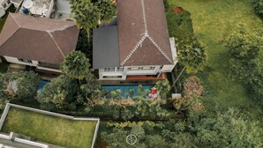A residential property with a swimming pool, multiple buildings, and surrounding greenery.
