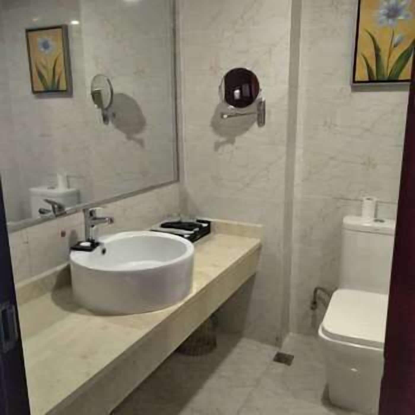 A modern bathroom with a white sink, mirror, and toilet.