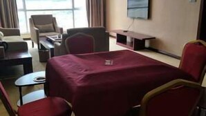 Una habitación de hotel con un ventanal grande, un televisor de pantalla plana, una mesa roja y varias sillas.