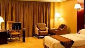 Una habitación de hotel con una cama, dos sillones, un escritorio y una lámpara.