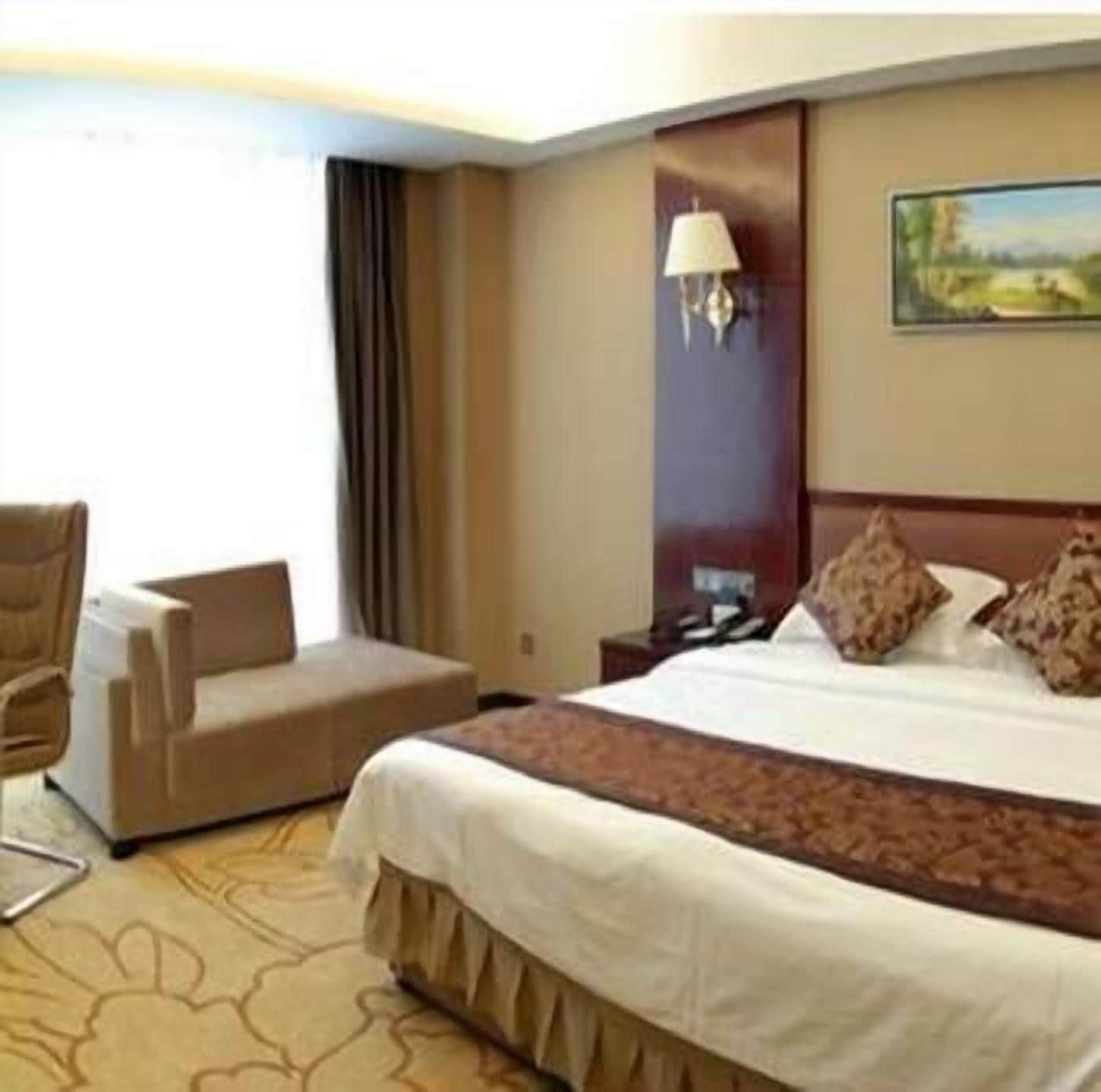 Habitación de hotel con una cama grande, un escritorio, una silla y un cuadro en la pared.