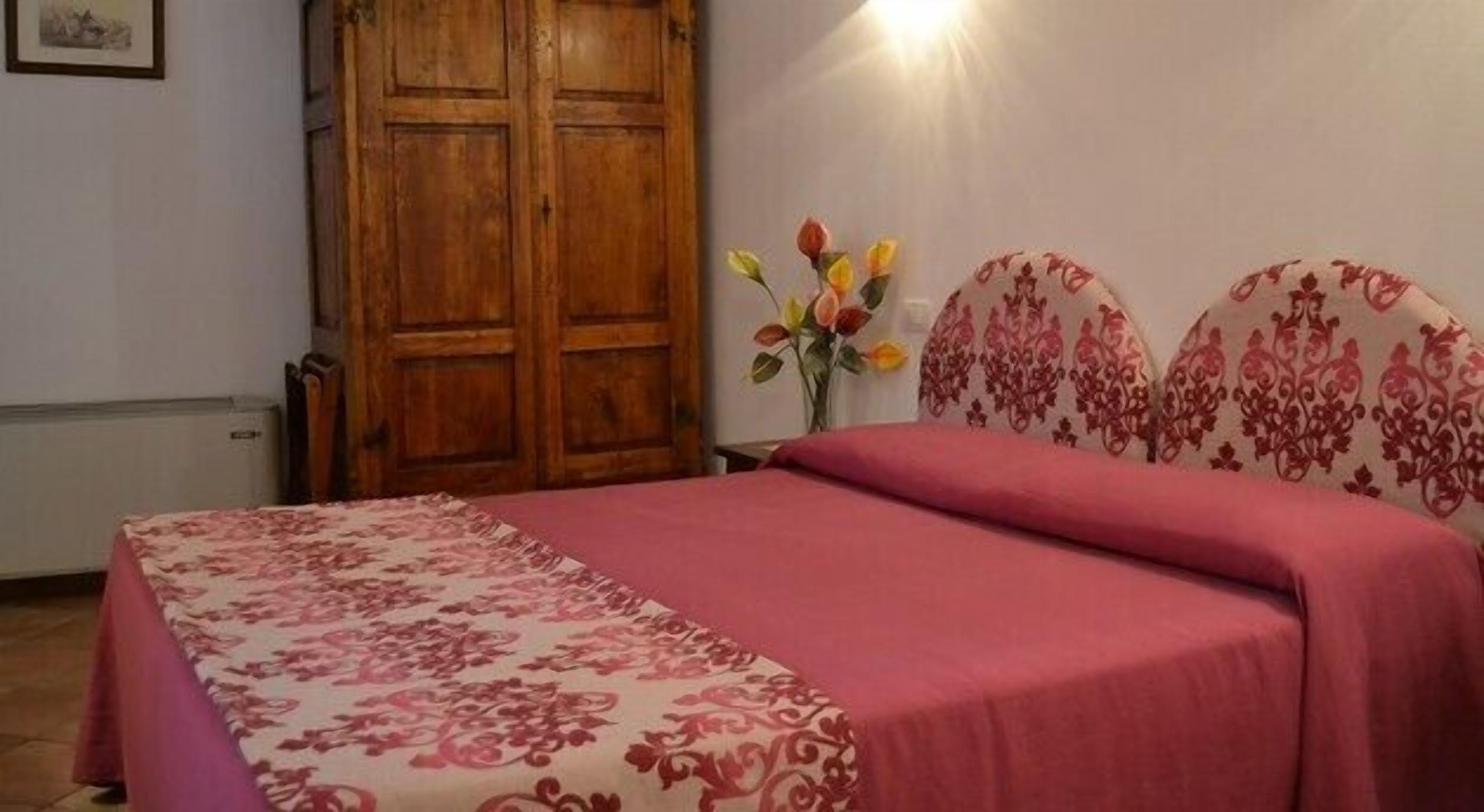 Un dormitorio con una cama, un armario de madera y un florero con flores.