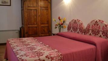 Un dormitorio con una cama, un armario de madera y un florero con flores.